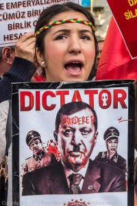 A young British Alevi protester holds a poster showing President Erdogan with blood dripping from his face and the word 'Murderer' aross his forehead at London protest in solidarity with those kiled in Ankara bombings.